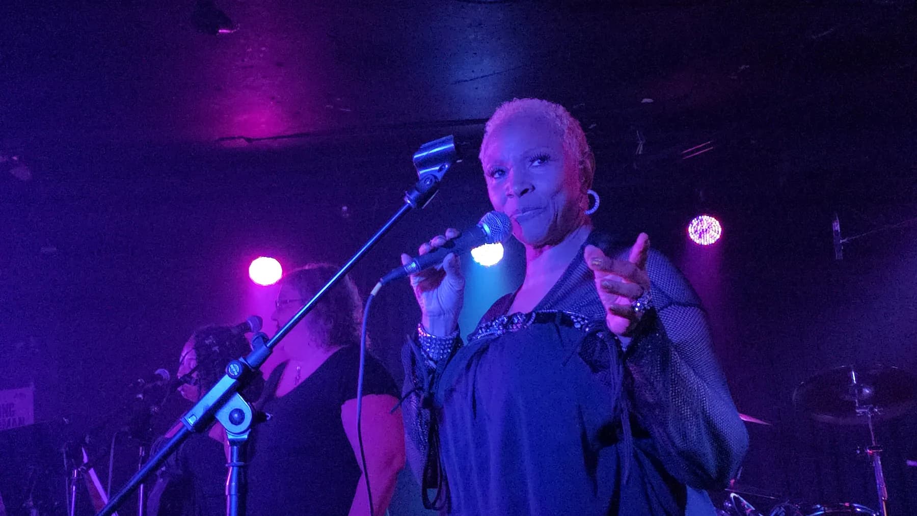 Cote Lind performing at a microphone under stage lights